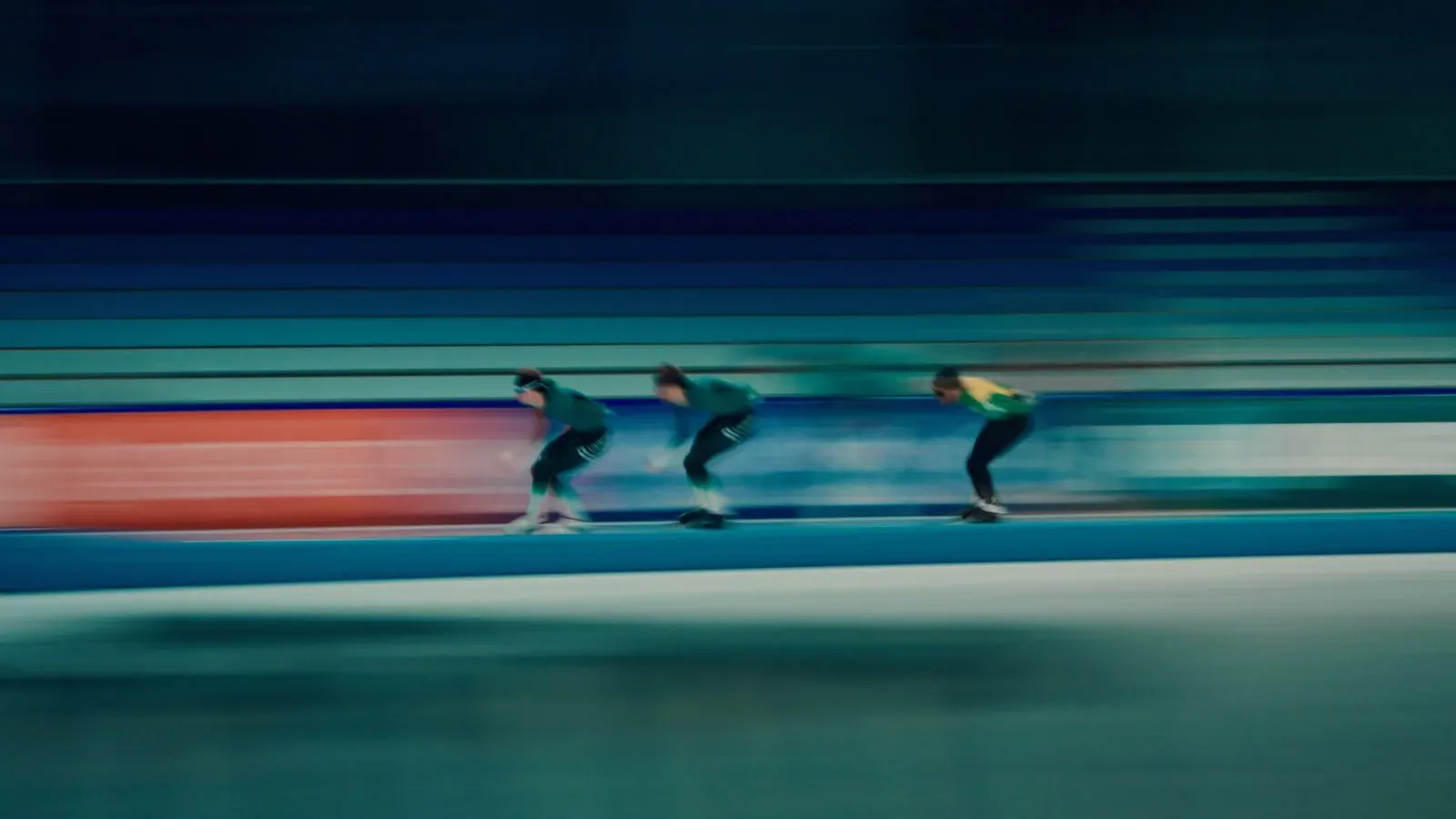 Drie schaatsers in een pakje op de baan